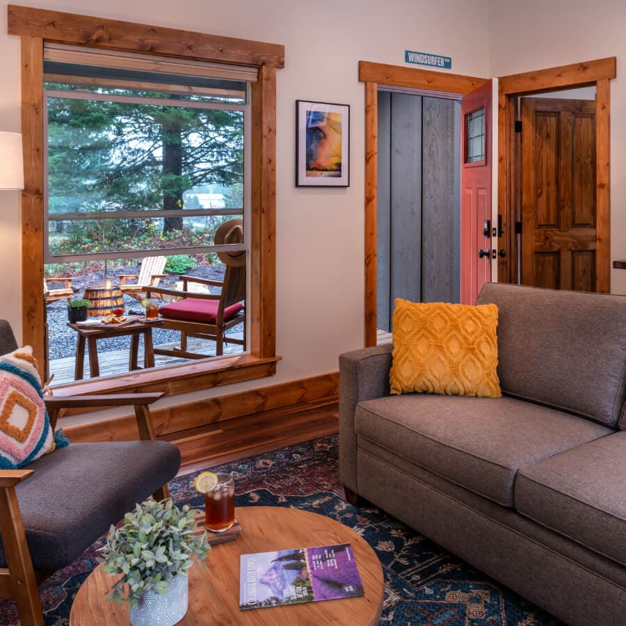 Cozy living room with a view of an outdoor seating area, featuring warm wooden accents and inviting decor.