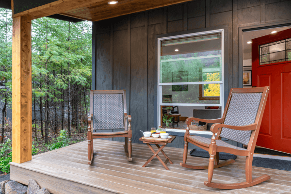 Cozy cabin porch with wooden chairs and peaceful views of trees.