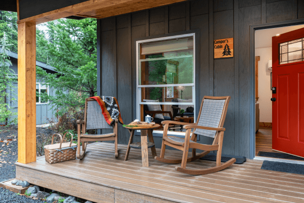 Cozy cabin porch with wooden chairs and peaceful views of trees.